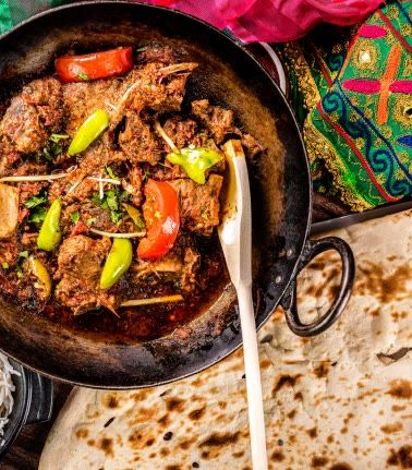 A karahi of slow-cooked lamb with green chillies, served with fresh naan.